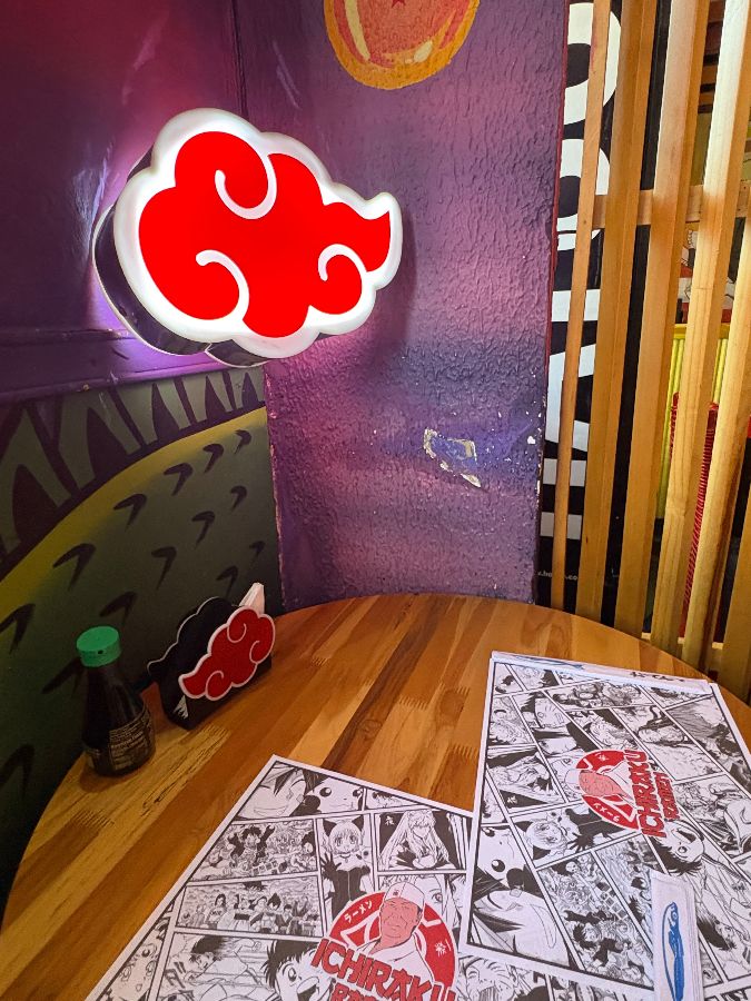 아카츠키 구름 모양의 네온사인 조명과 만화풍 종이 매트가 놓인 테이블