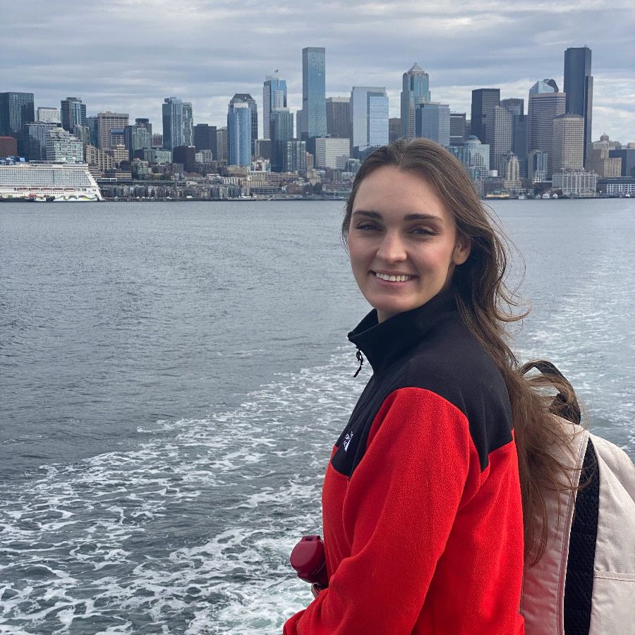 배 위에서 도시 스카이라인을 배경으로 뒤를 돌아보며 미소 짓는 한 여성의 모습. 여행의 즐거움과 도시의 풍경이 함께 담겨 있습니다.