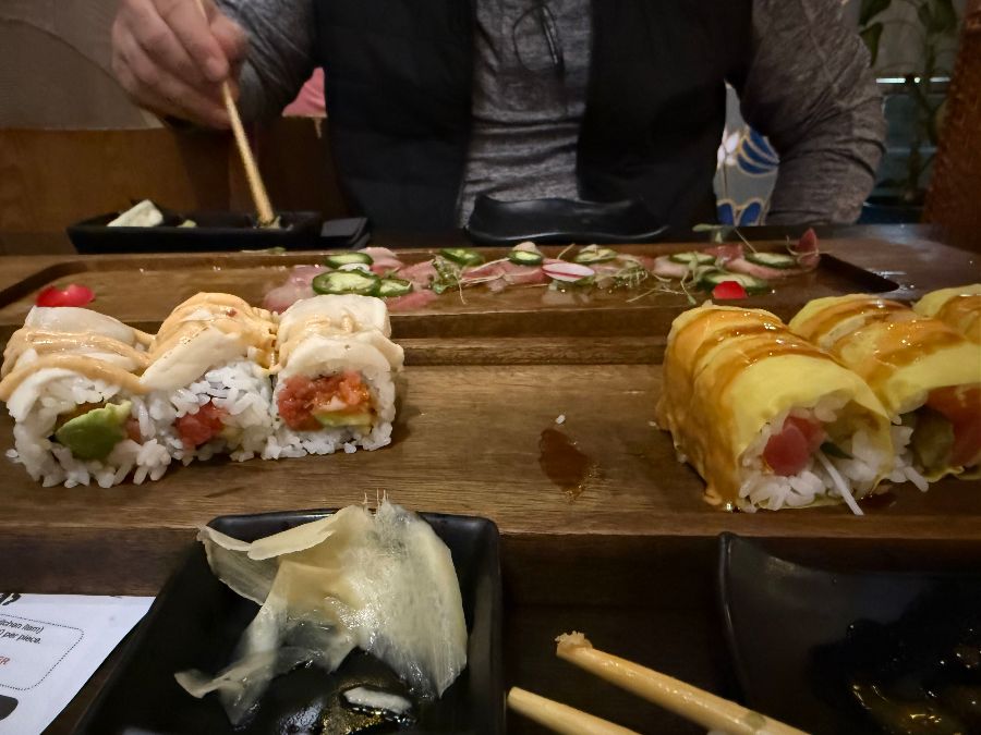 다양한 종류의 스시 롤이 나무 도마 위에 올려져 있다.