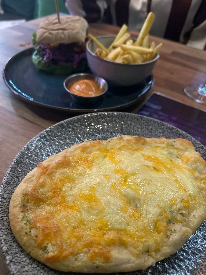 채식 버거와 치즈가 올려진 빵, 감자튀김이 함께 놓인 접시