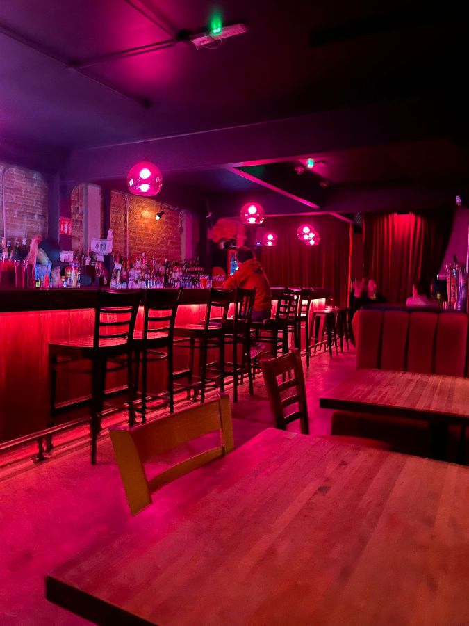 붉은 조명과 둥근 펜던트 조명이 있는 바 내부