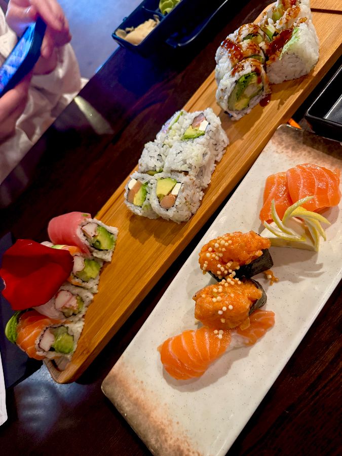 다양한 스시 롤과 사시미가 나무 플레이팅 위에 올려져 있다.