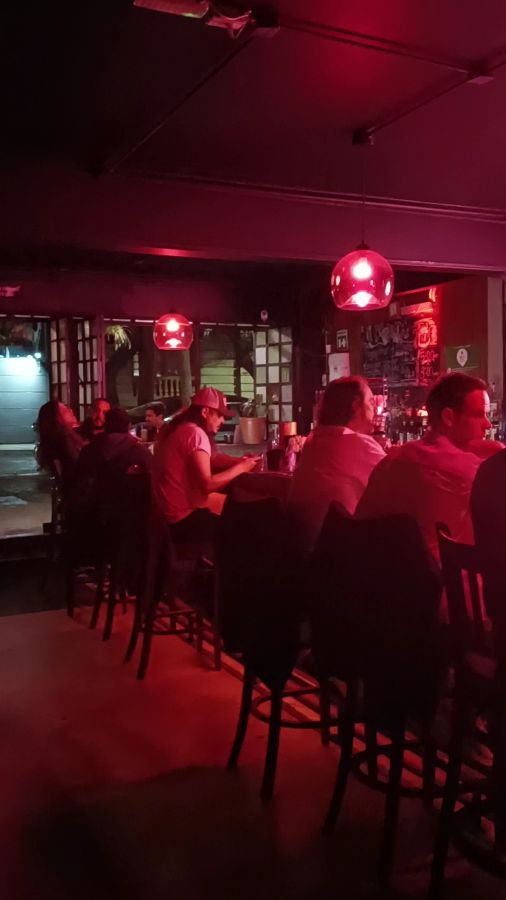 바 내부 전경, 붉은 조명 아래 바에 앉은 사람들