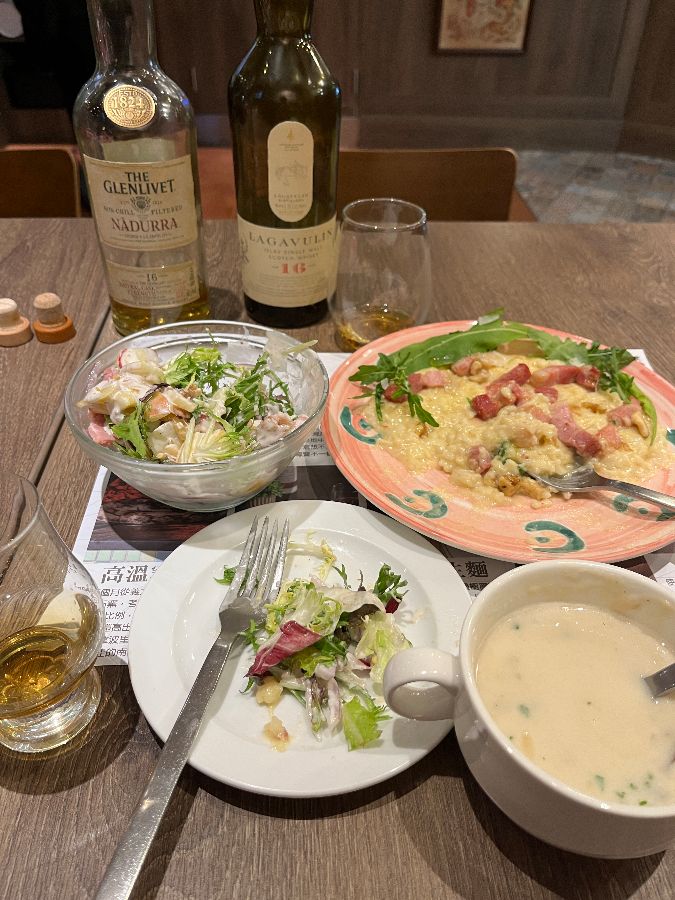 테이블 위에 놓인 샐러드, 파스타, 그리고 위스키