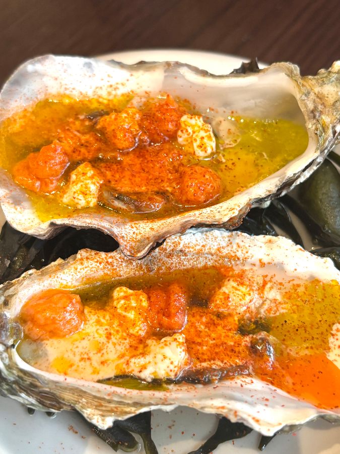 정갈하게 세팅된 식탁, 와인잔과 식기류, 메뉴판이 보인다.