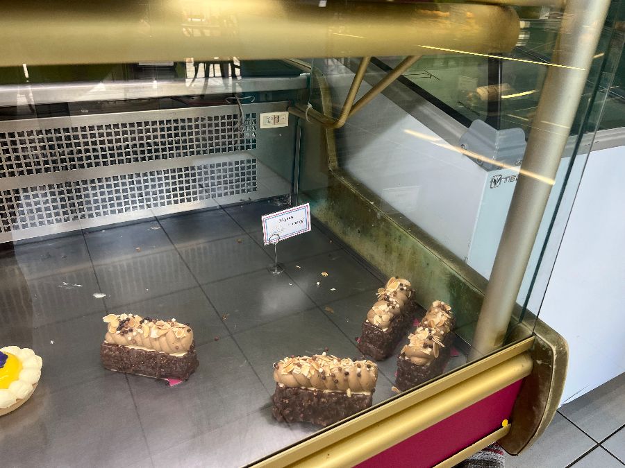 페이스트리가 거의 다 팔리고 몇 개만 남아 있는 쇼케이스의 모습. 빈 공간이 많이 보여 일찍 방문하지 않으면 인기 메뉴를 맛볼 수 없음을 시사합니다.