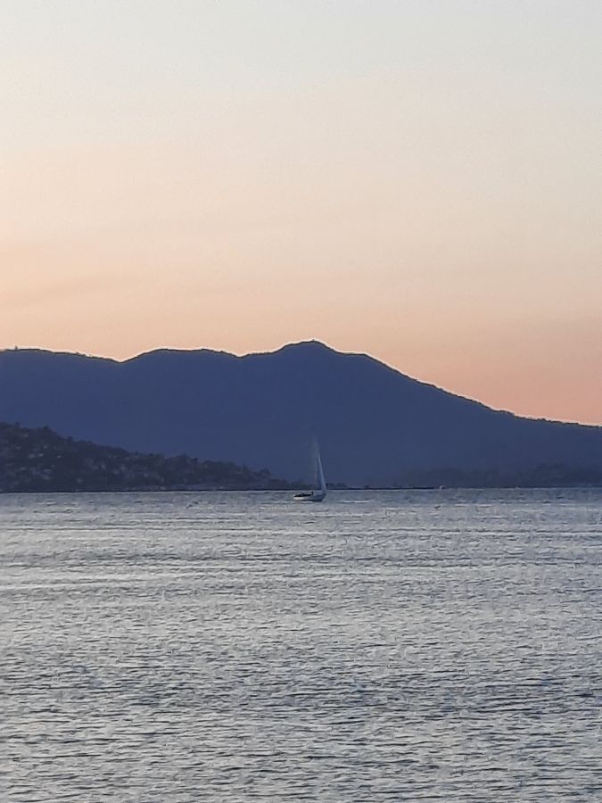 잔잔한 바다 위에 떠 있는 요트와 멀리 보이는 산