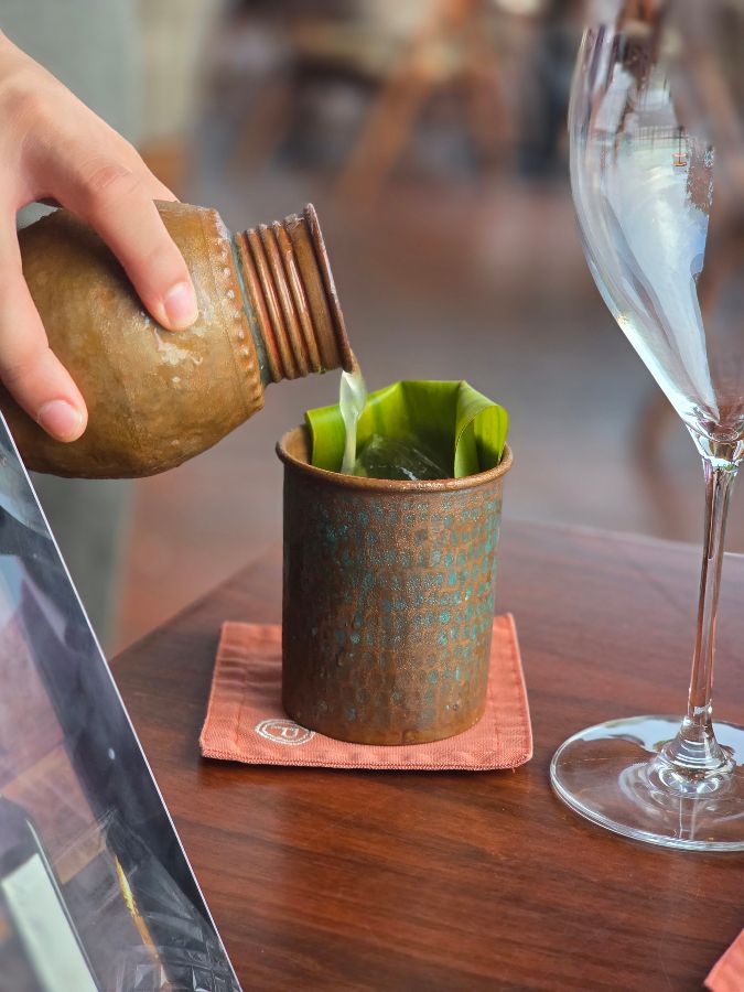 투박한 질감의 컵에 담긴 시그니처 칵테일. 붉은색과 초록색이 어우러진 색감과, 잔 위에 얹어진 라임이 인상적이다.