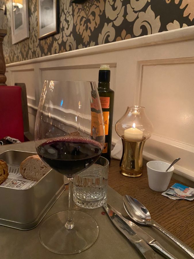 따뜻한 조명 아래 와인과 식전빵이 놓인 테이블