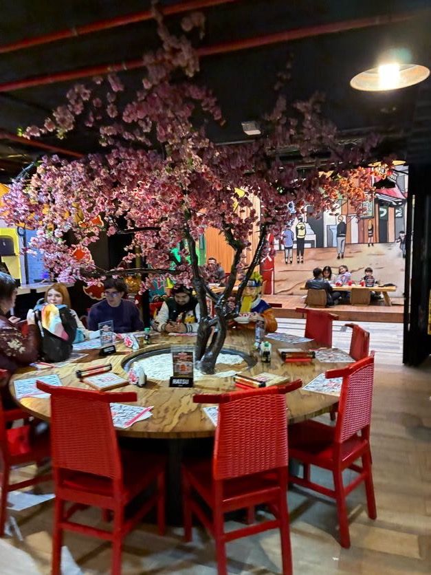 화려한 벚꽃나무 조형물 아래 원형 테이블과 식사하는 사람들