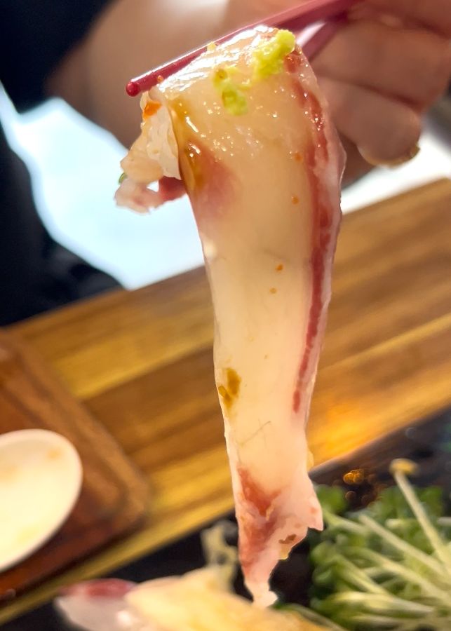 젓가락으로 집은 꼬리 긴 초밥