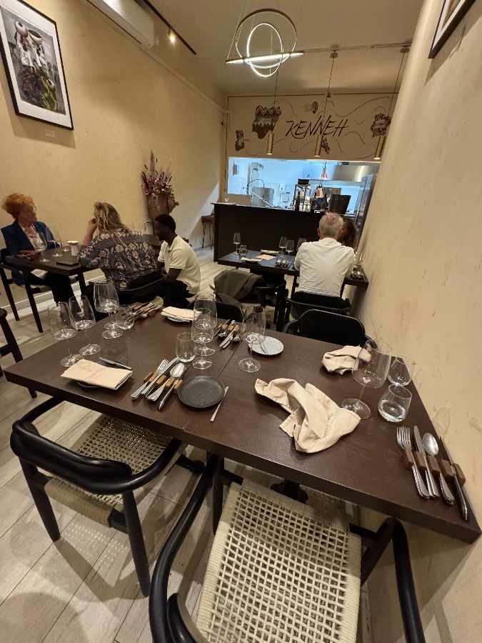 레스토랑 내부, 여러 손님들이 식사를 하고 있고, 오픈 키친이 보인다.