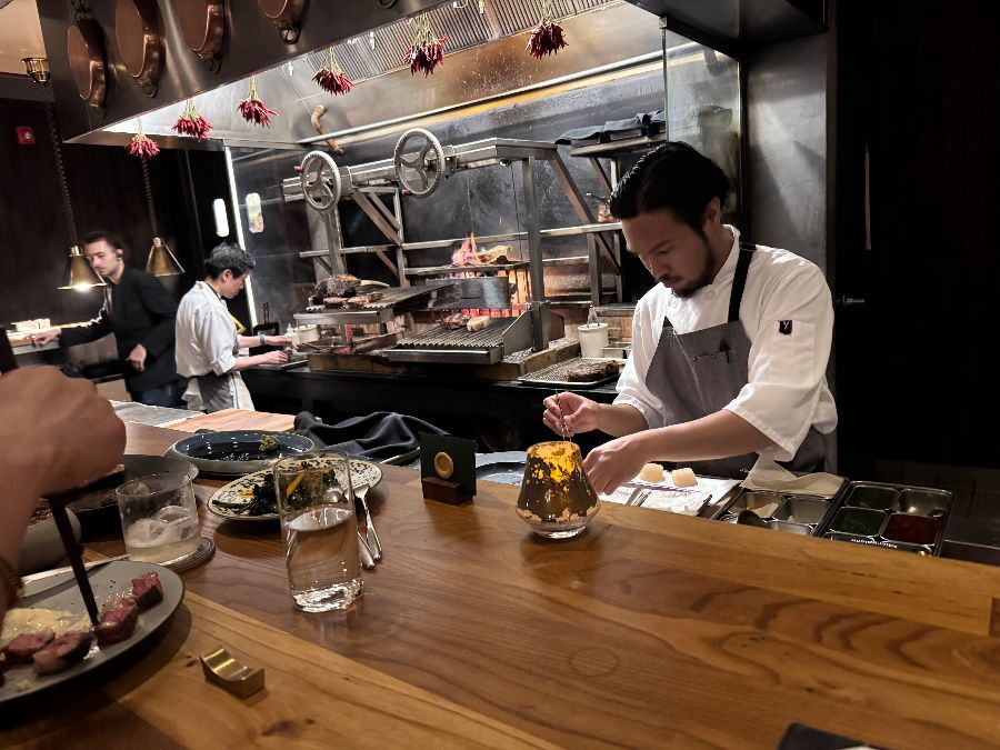 오픈 키친에서 장작불에 고기를 굽는 모습