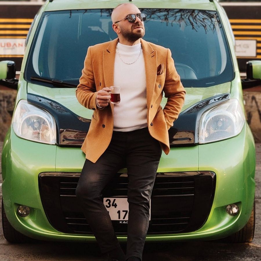 차에 기대어 커피를 마시는 남성